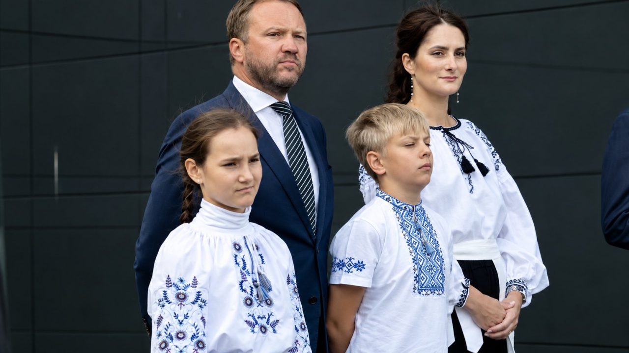 Учасники церемонії підняття прапора у Таллінні: чоловік у темному костюмі, двоє дітей і жінка у вишиванках