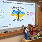 A screen reading “Nezlamna. You are not alone” and colourful motanka dolls made at the workshop